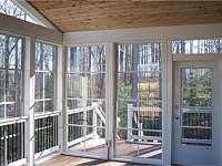 <b>View from the inside of the screened porch. This photo highlights the Eze-Breeze sliding panel system that allows you to use your room all year round. Even the door has an Eze-Breeze vertical four track system. The structure has composite deck boards, white vinyl railing with black aluminum balusters. The ceiling of the screened porch is finished in tongue and groove cedar, and all the support beams are wrapped in low maintenance vinyl. You can also see an electrical outlet was installed for electricity needs inside the room.</b>